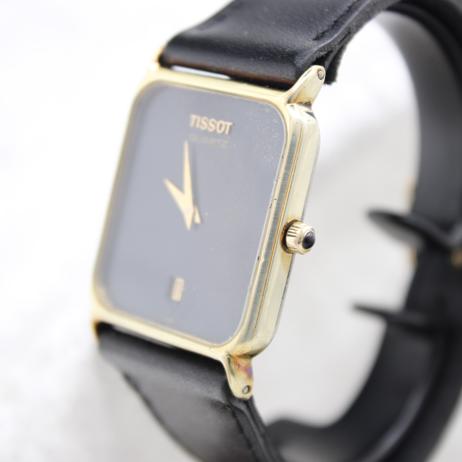 Side profile of the Tissot watch, showcasing its slim gold-tone case and crown details.