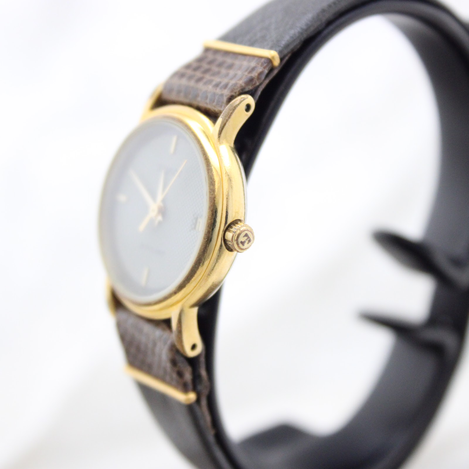 Side profile of the Tissot Stylist watch, highlighting its slim gold-tone case and crown details.
