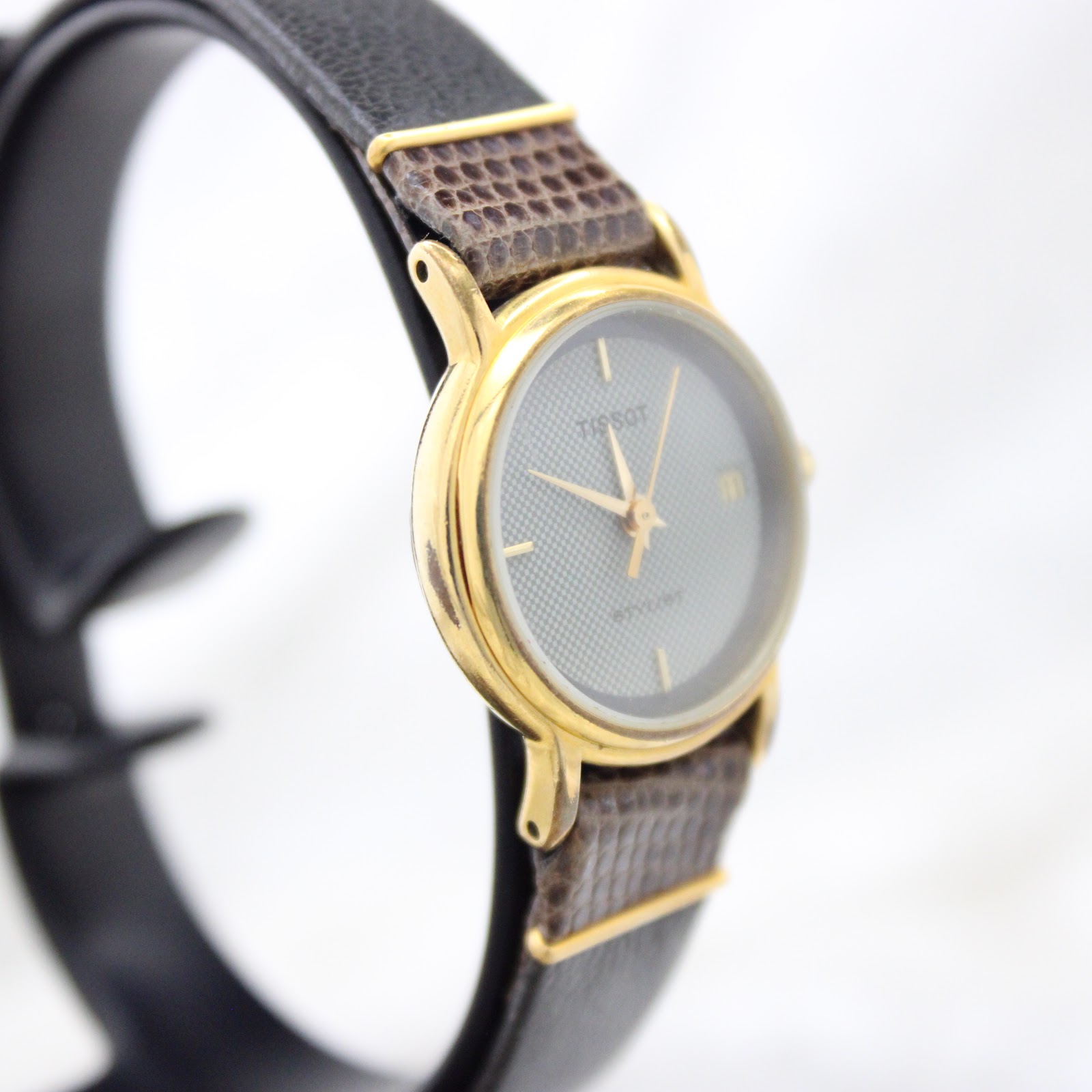 Close-up of the Tissot Stylist dial, showing the textured grey centre, black outer ring, and date complication.