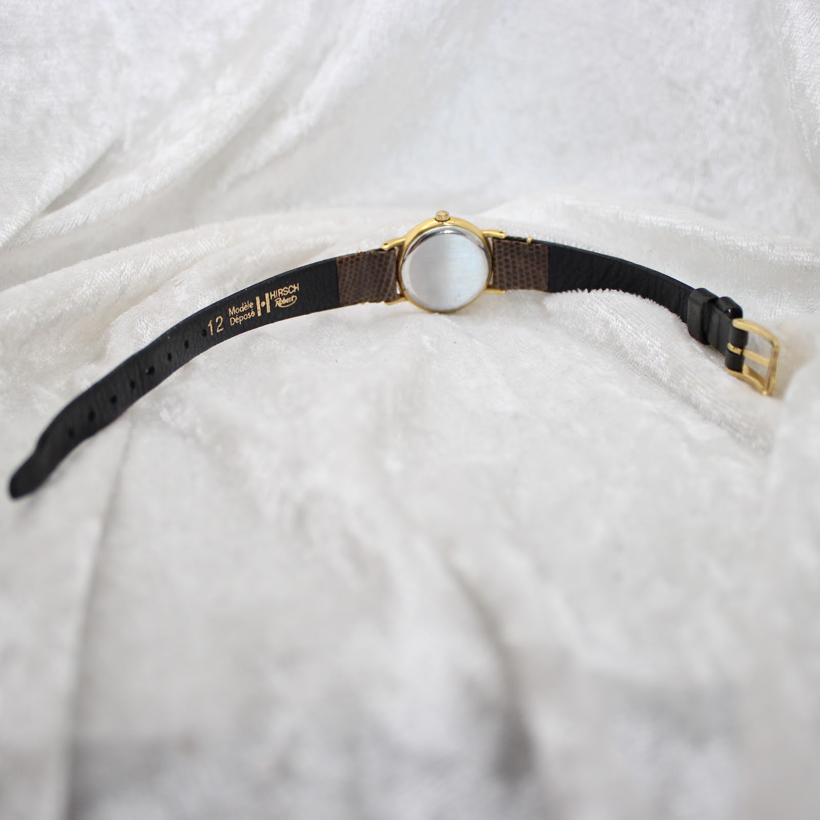 Detail shot of the brown leather strap and its buckle on the Tissot Stylist watch.