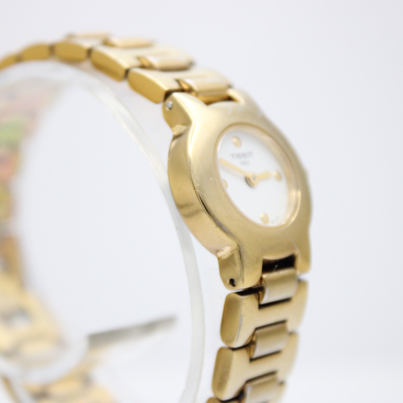 Angled view of the Tissot G331K gold watch, showing the left side of the case and integrated bracelet.