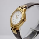 Angled side view of the Tissot Stylist watch, highlighting the gold-tone case and brown leather strap on a display stand.