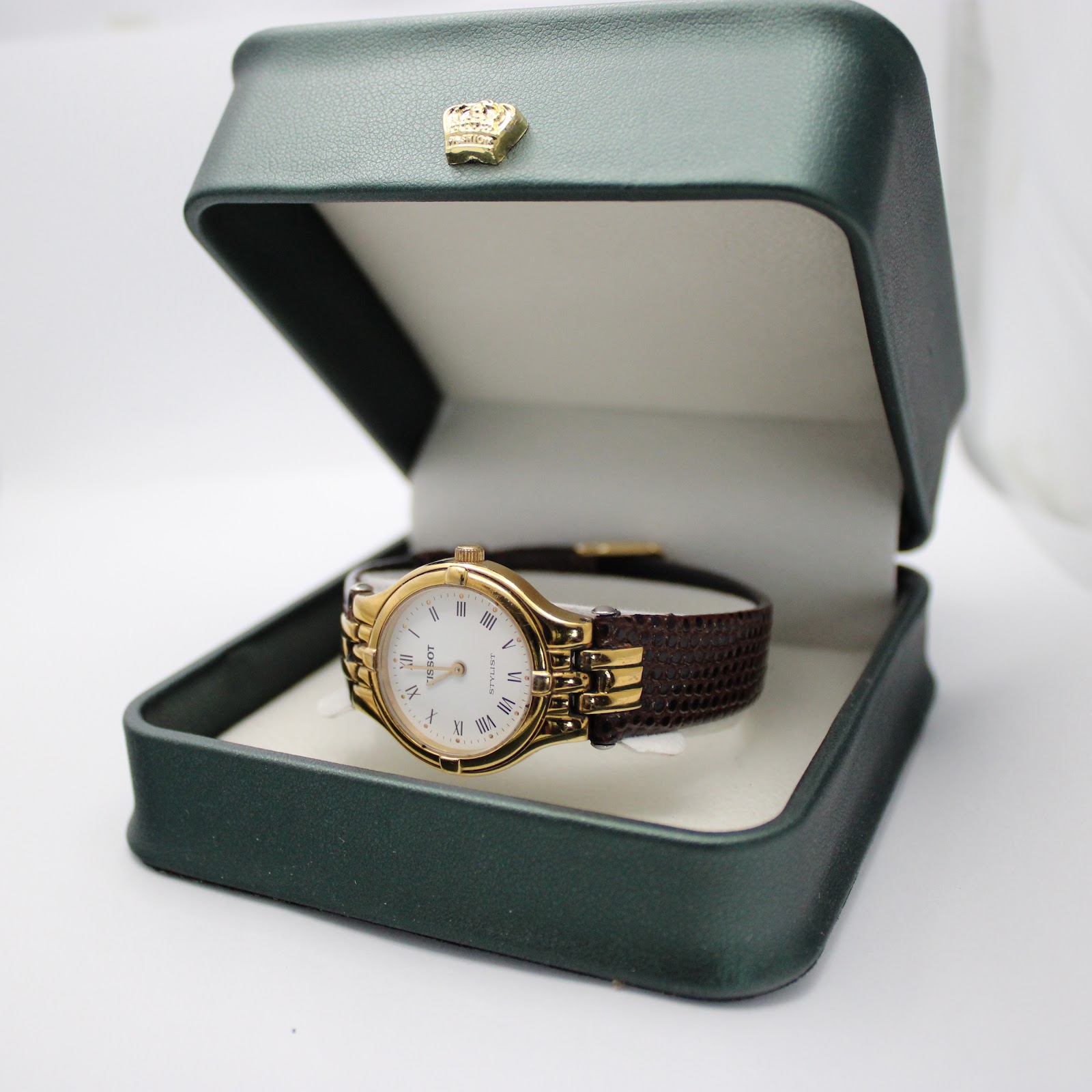 The Tissot Stylist watch displayed inside a green watch box with a gold crown emblem.