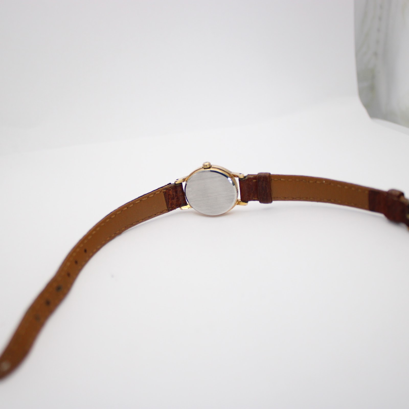Back view of the Tissot watch, showing the brushed stainless steel case back and the full length of the brown leather strap with its buckle.