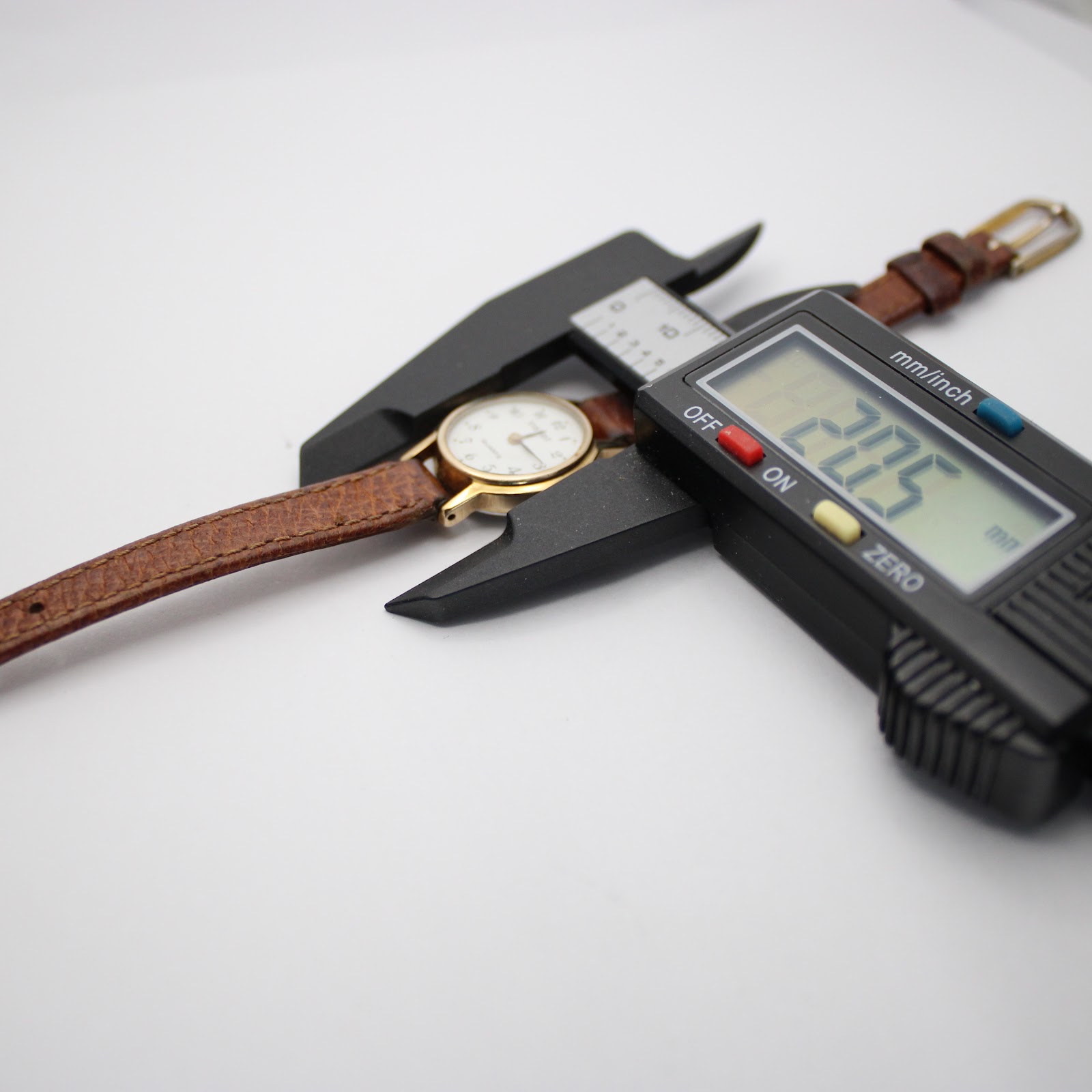 Overhead view of the Tissot watch with a digital caliper measuring the case diameter at 20.5mm, confirming the watch's small size.