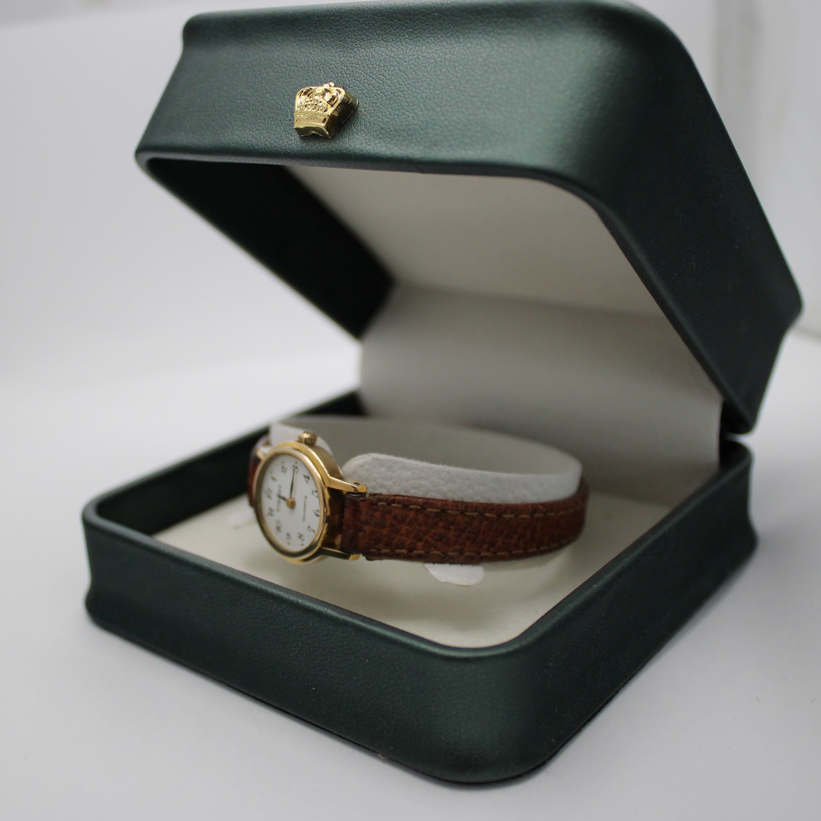 The Tissot women's watch resting inside an open dark green presentation box with a gold crown emblem on the lid.