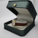 The Tissot women's watch resting inside an open dark green presentation box with a gold crown emblem on the lid.
