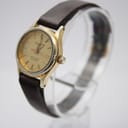Angled three-quarter view of the Tissot Seastar watch, showing the right side of the gold-tone case, crown, and brown leather strap.