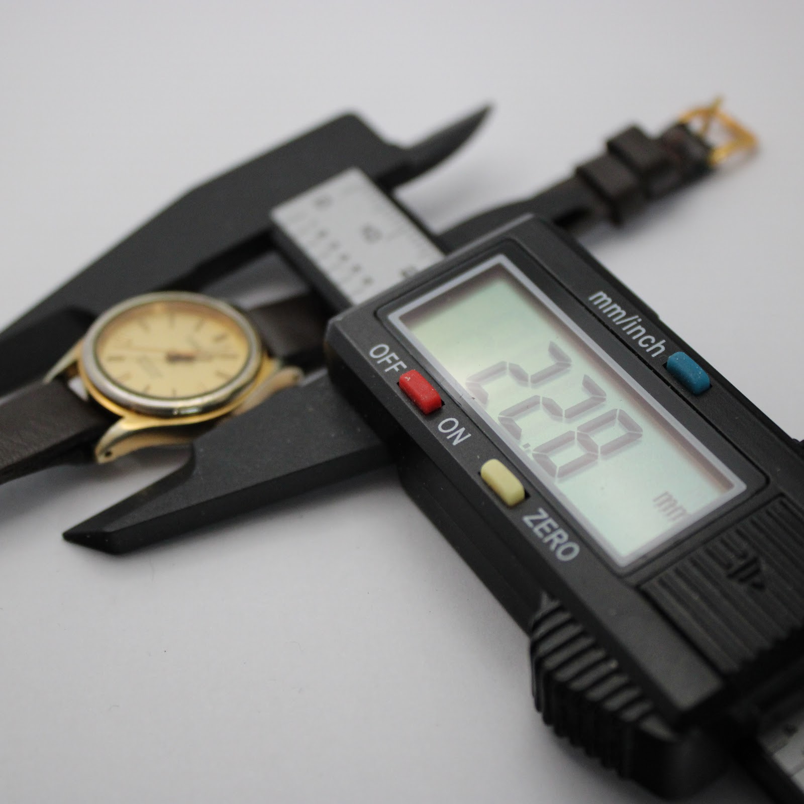 Close-up of a digital caliper measuring the watch case diameter at precisely 22.8mm, with the watch in the background.
