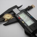 Close-up of a digital caliper measuring the watch case diameter at precisely 22.8mm, with the watch in the background.