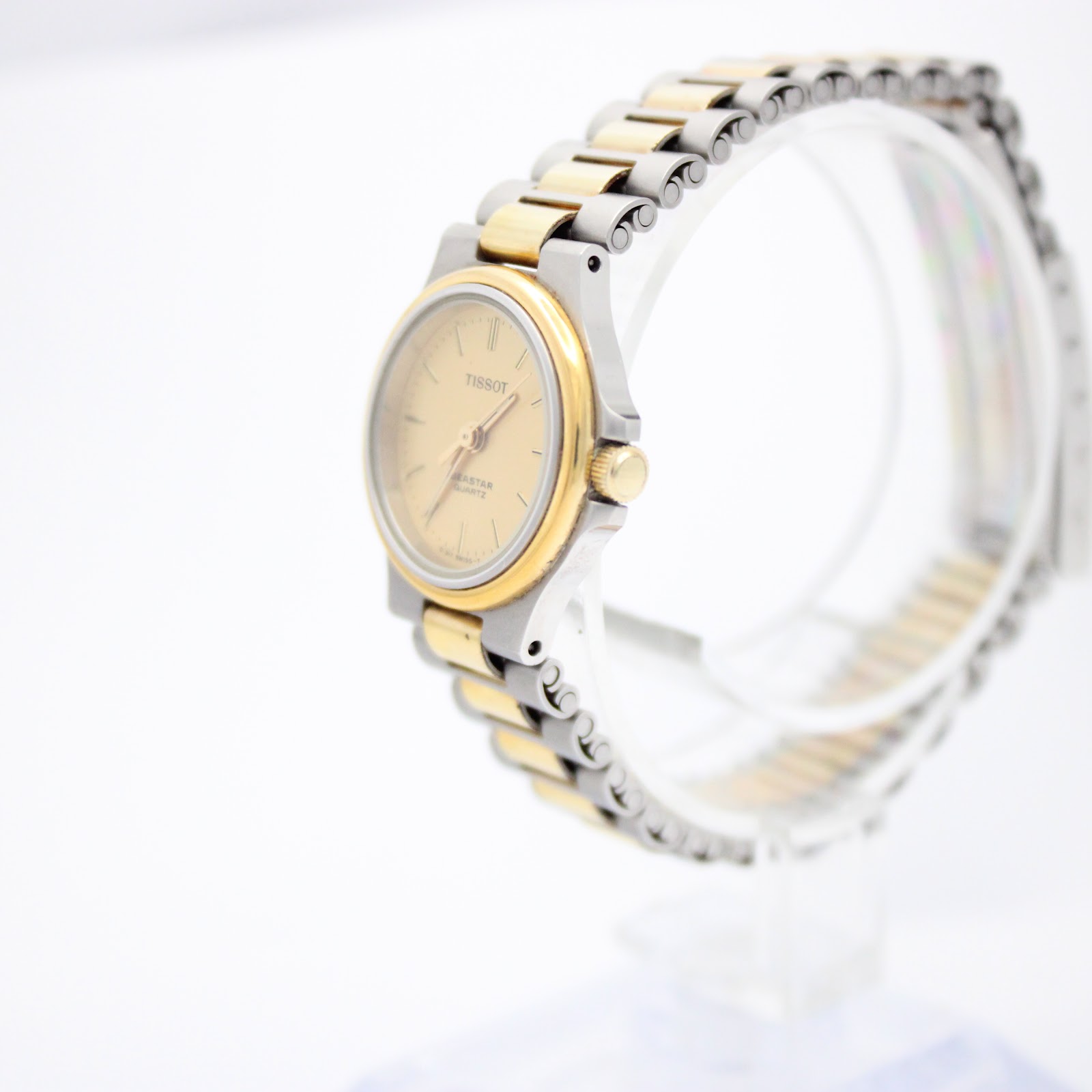 Angled side view of the vintage Tissot Seastar, highlighting the two-tone bracelet and gold-tone crown, presented on a clear stand.