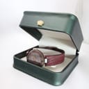 The Tissot Rock Watch R150 with its red stone case and strap, presented in an open dark green display box.