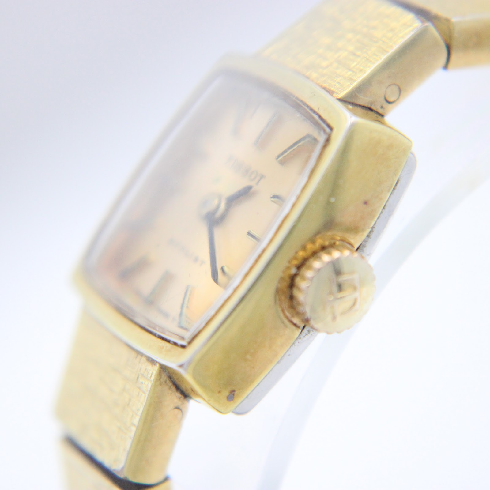 Close-up of the watch dial and signed crown with 'T' logo.
