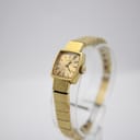 Angled front view of the Tissot Stylist on a clear display stand, showing the integrated gold-filled bracelet.