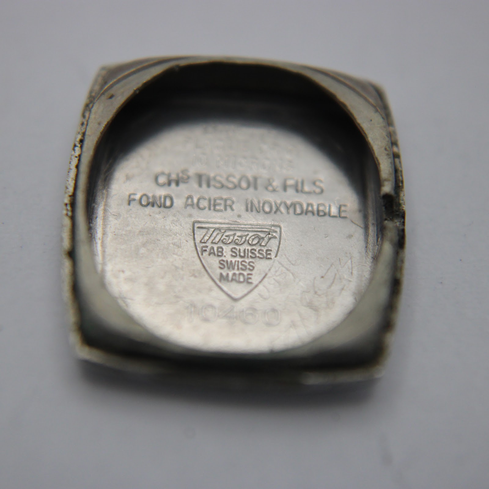 Interior view of the case back showing 'CHS TISSOT & FILS', 'FOND ACIER INOXYDABLE', 'FAB. SUISSE SWISS MADE', and reference '10460'.