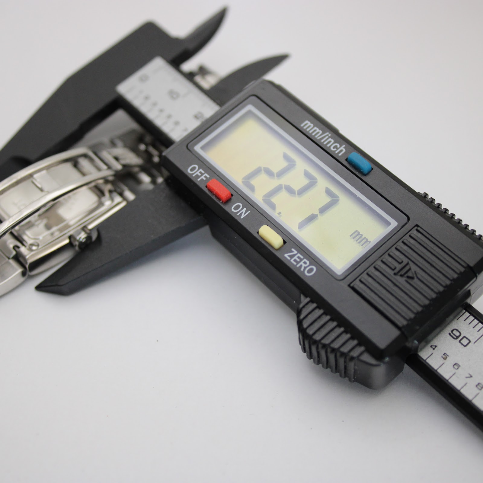 Digital caliper measuring the watch case, displaying a precise measurement of 22.7 mm.