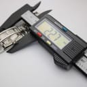 Digital caliper measuring the watch case, displaying a precise measurement of 22.7 mm.