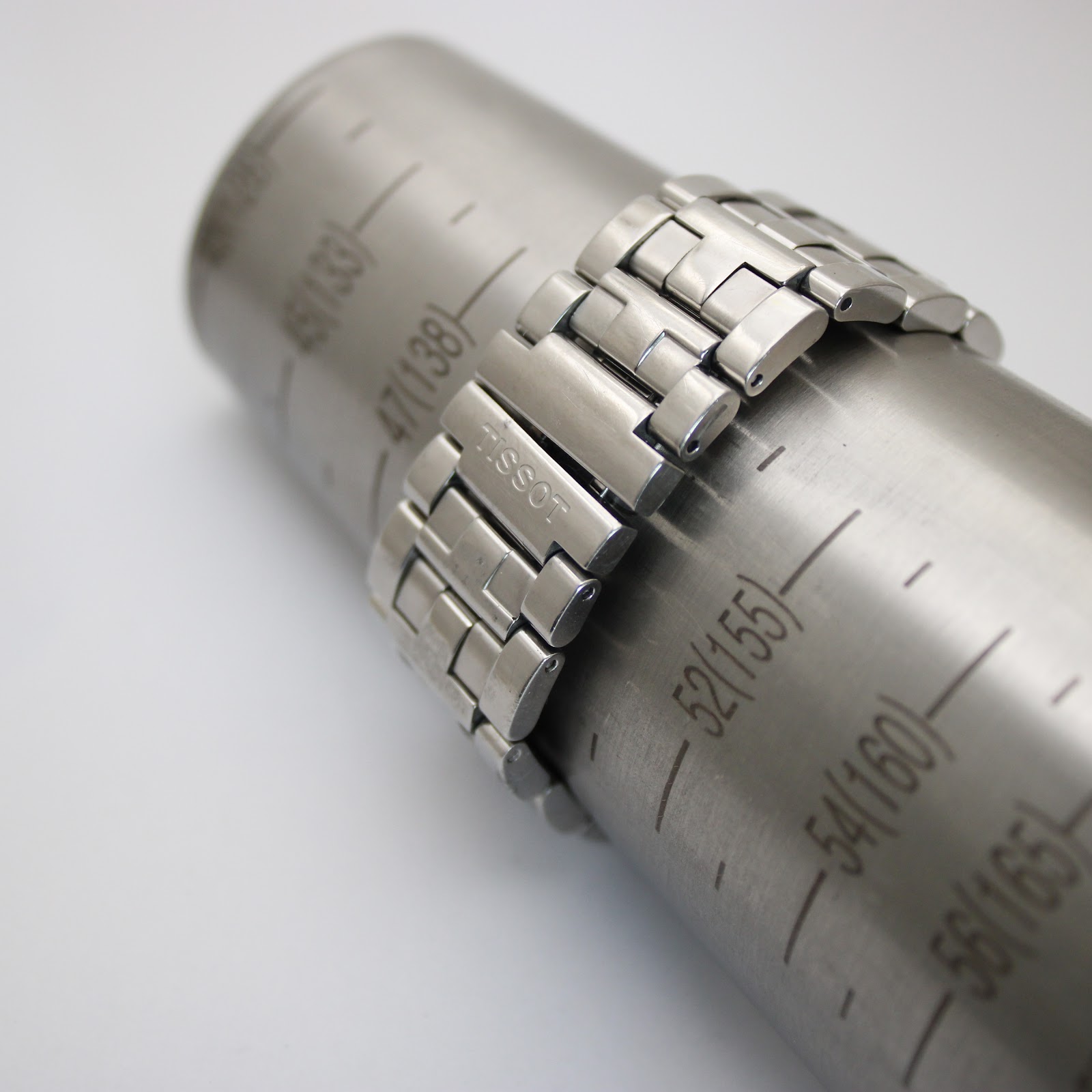 Tissot stainless steel bracelet wrapped around a wrist sizing gauge, showing a fit of approximately 150mm / 15cm, with a signed Tissot clasp visible.