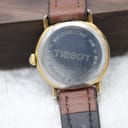 Close-up of the watch case back, showing "Waterresistant 30M", "Tissot", "Stainless Steel", "Mineral Glass", and model number C225K. The gold-tone underside of the lugs is also visible.