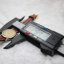 Top-down view of the Tissot watch with digital calipers showing a measurement of 25.1mm across the case, resting on a white textured surface.