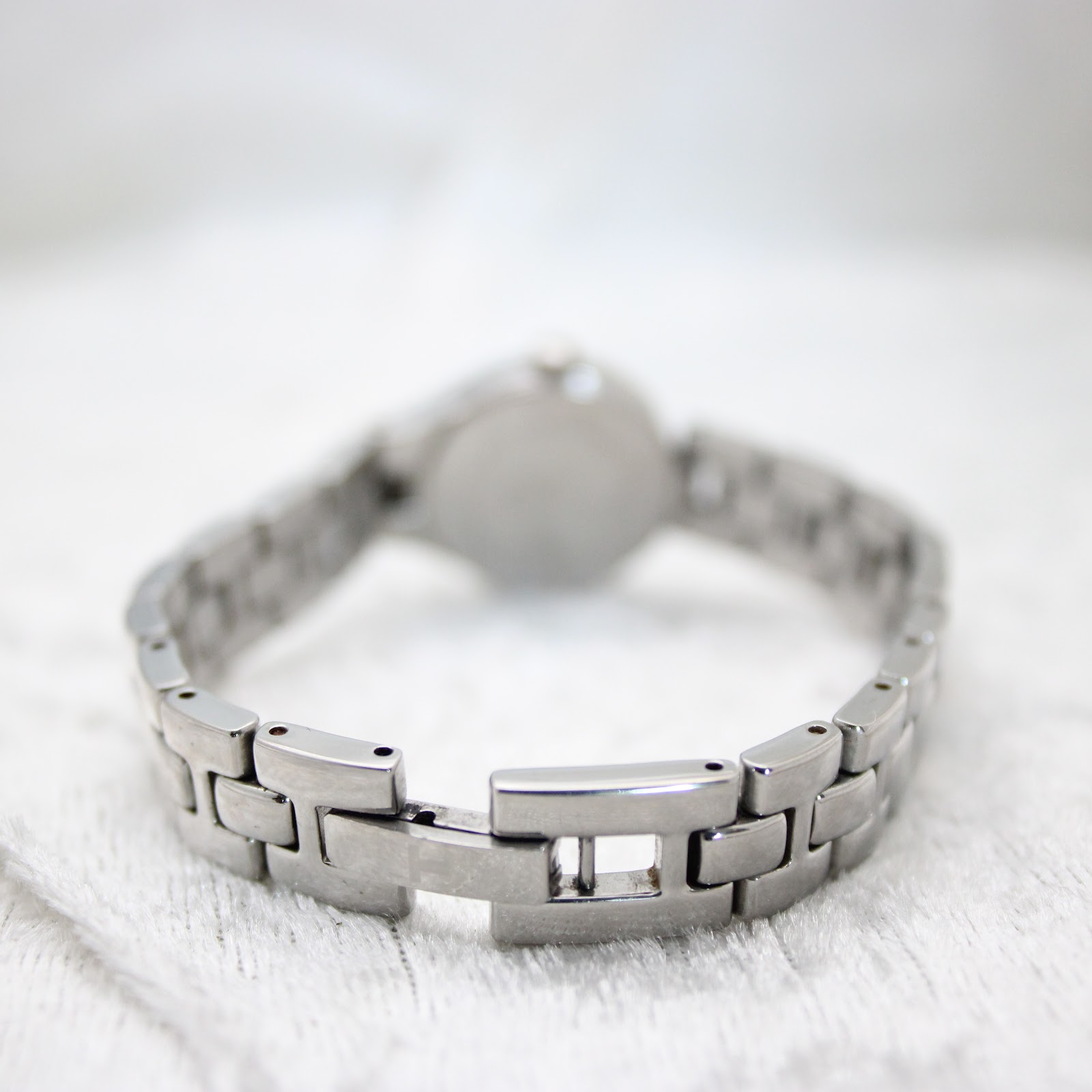 Rear view of the Tissot G334's integrated stainless steel bracelet with its folding clasp open, laid against a textured white background.