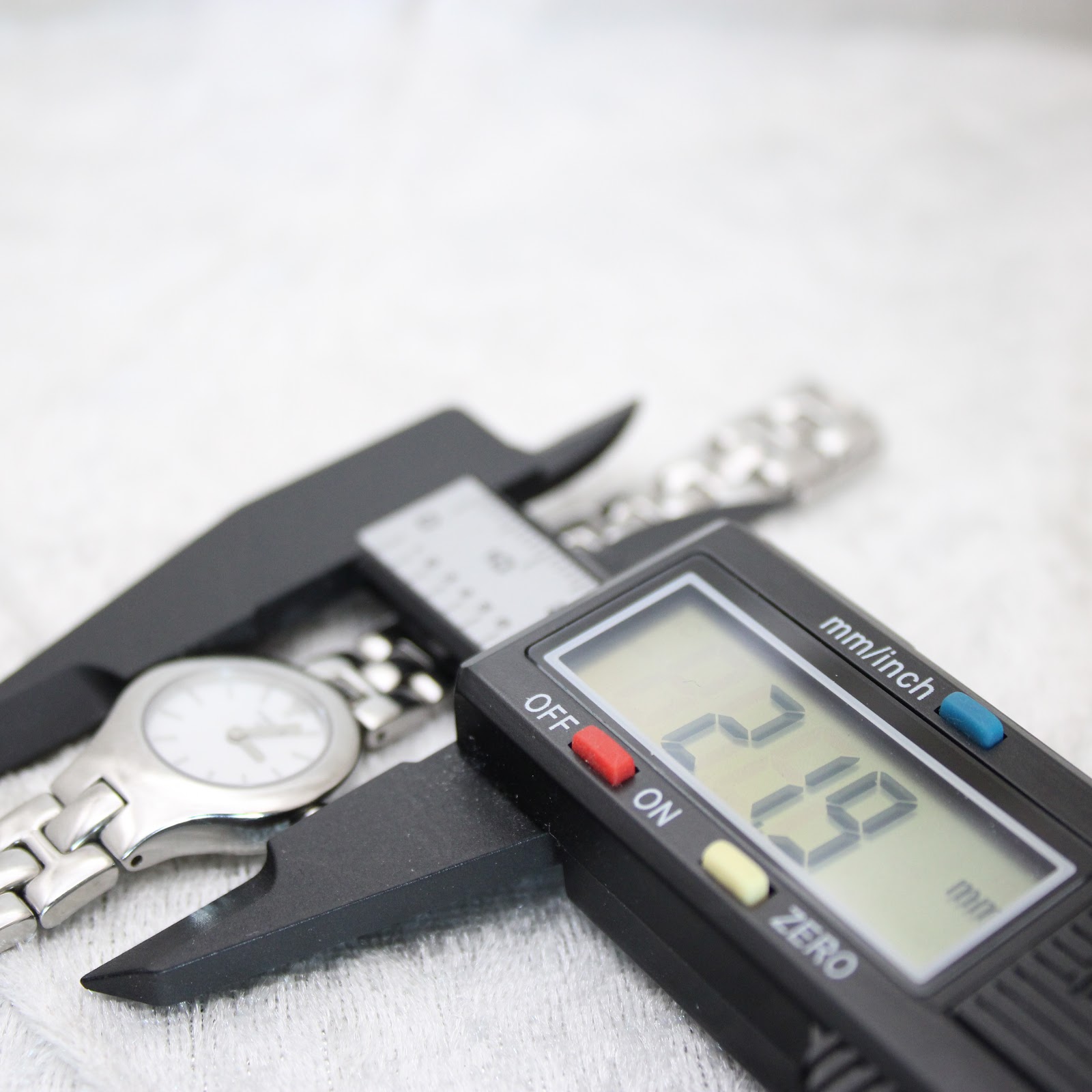 A digital caliper measuring the Tissot G334 watch case, displaying a precise diameter measurement of 21.9mm on its screen.