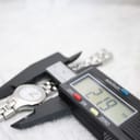 A digital caliper measuring the Tissot G334 watch case, displaying a precise diameter measurement of 21.9mm on its screen.