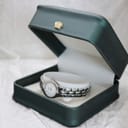 The Tissot G334 watch nested inside a dark green presentation box with a decorative gold crown emblem on the lid.