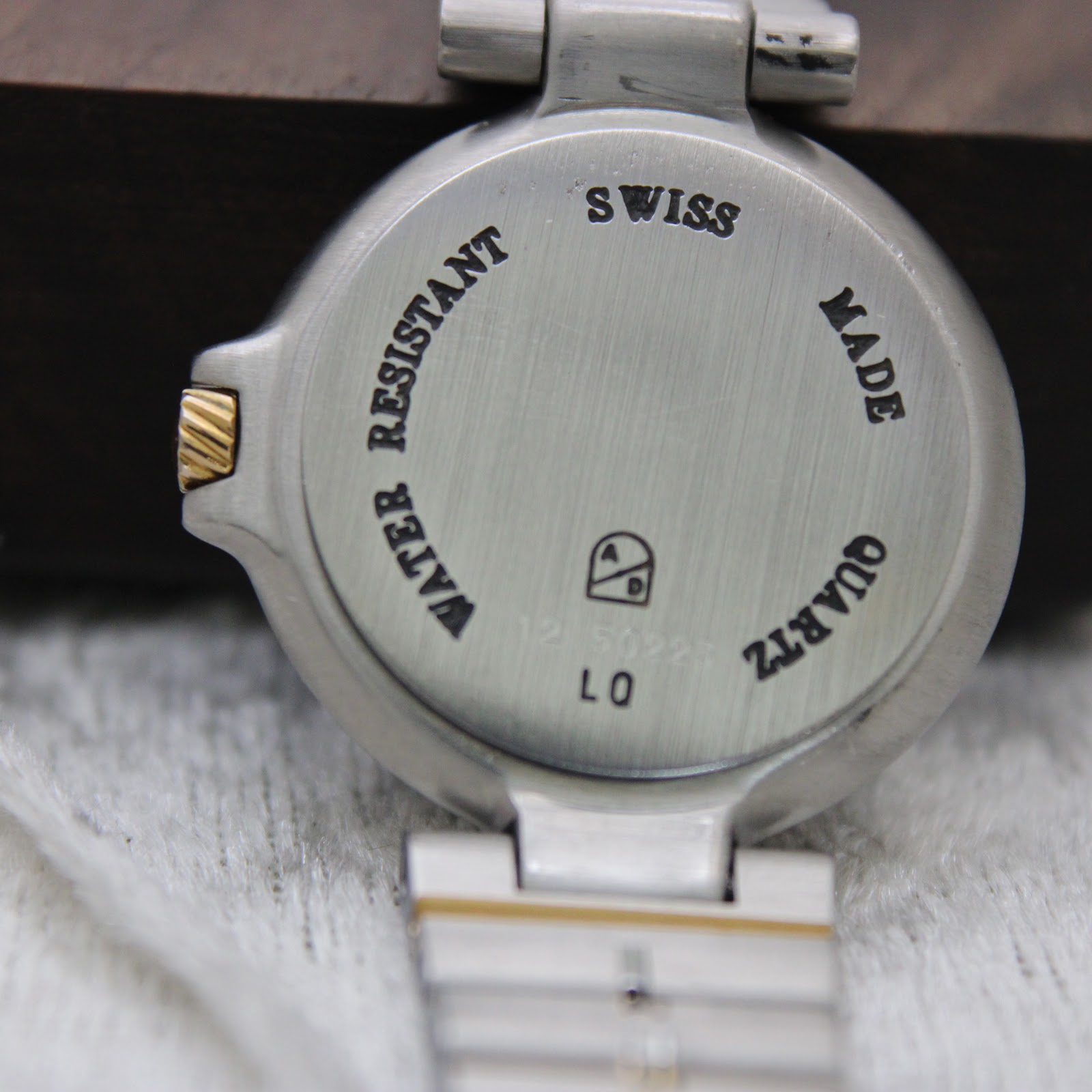 Close-up of the watch case back, showing 'Swiss Made Quartz Water Resistant' engraving and serial number '12 50223'.