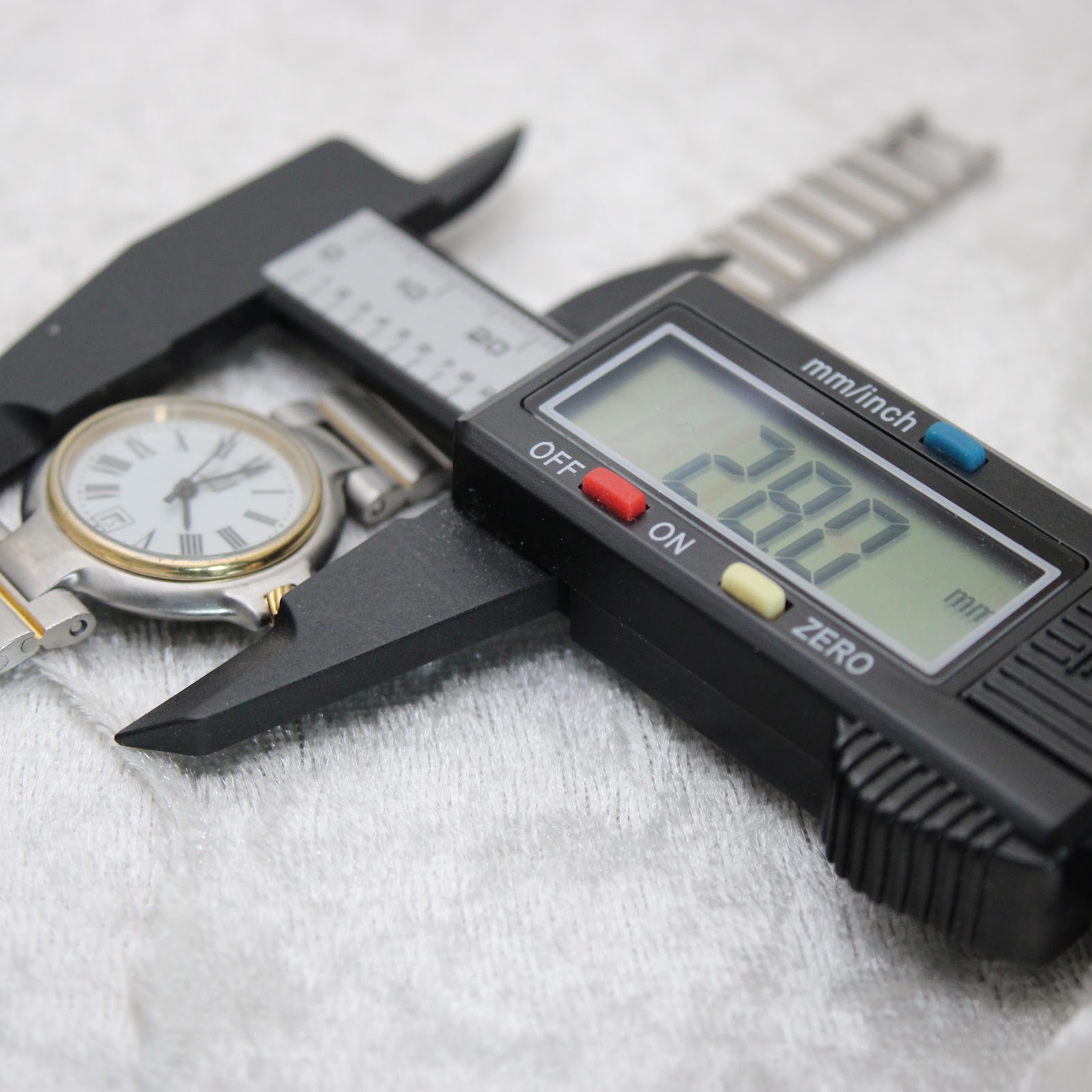 Digital caliper measuring the watch case, displaying a precise diameter of 28.0mm.