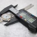 Digital caliper measuring the watch case, displaying a precise diameter of 28.0mm.