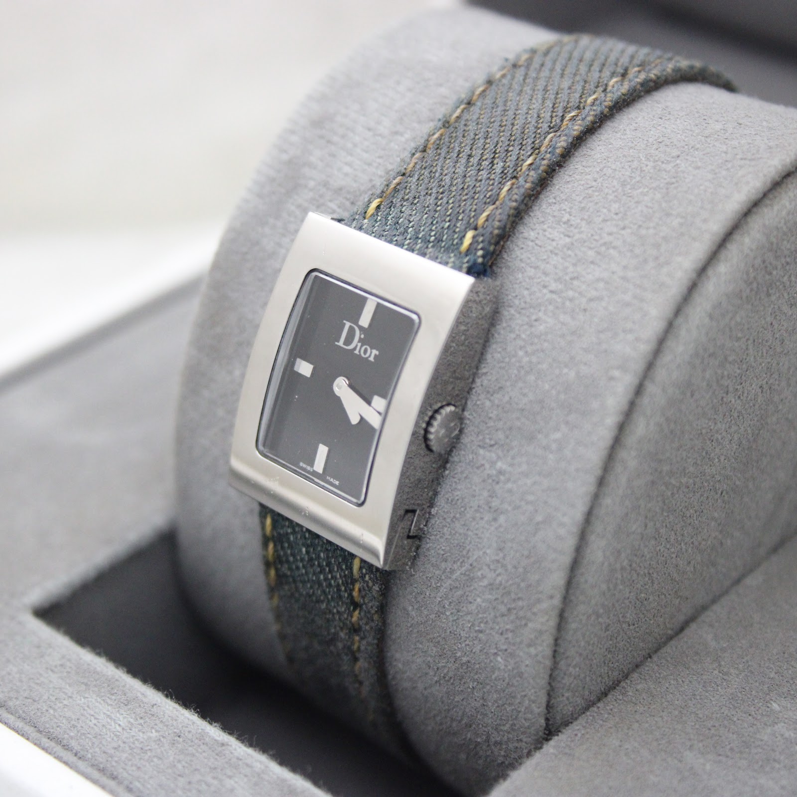 Angled view of Christian Dior D78-109 watch on grey display cushion, showing side of rectangular steel case and crown.