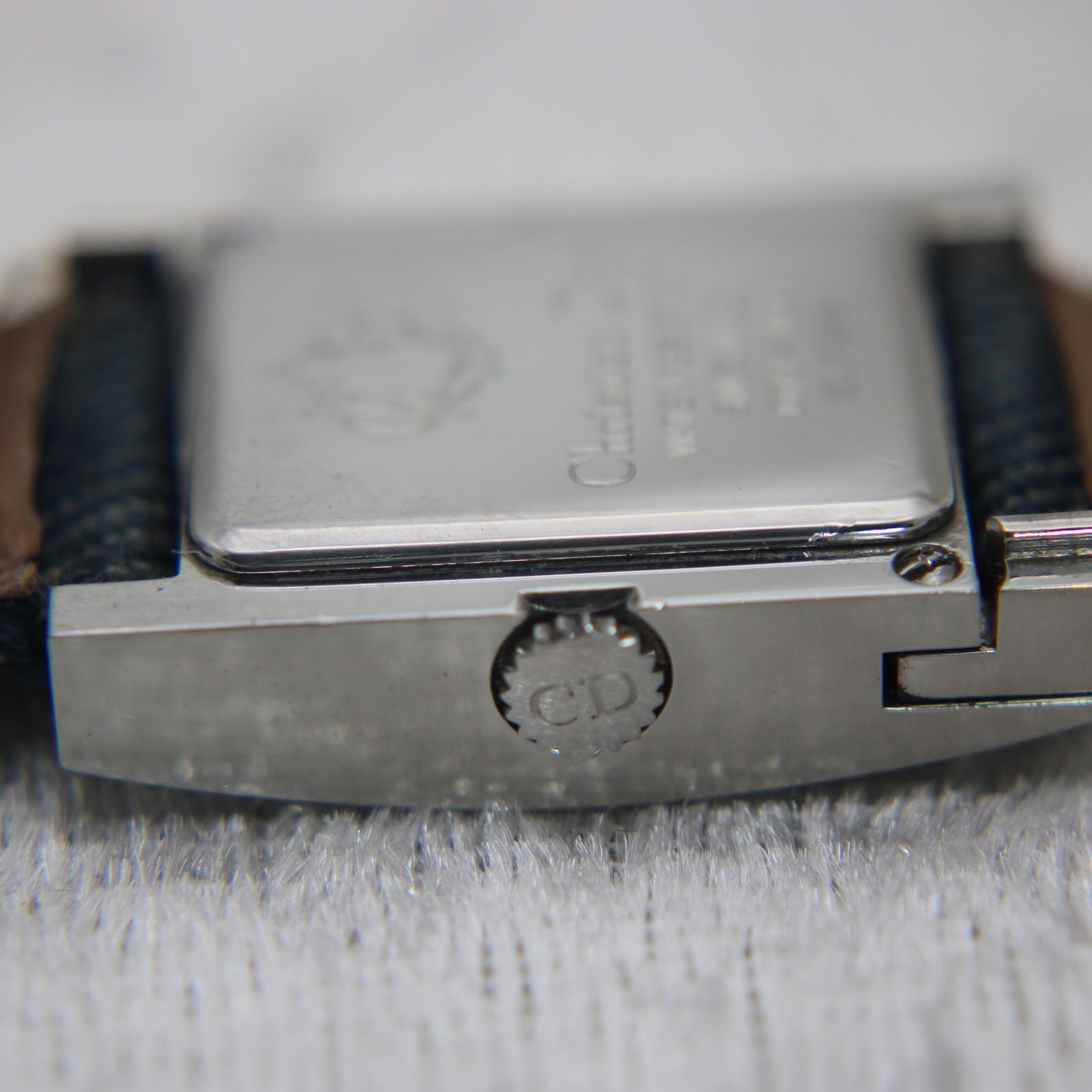 Side view of the watch case, showing the ridged crown with a "CD" logo.