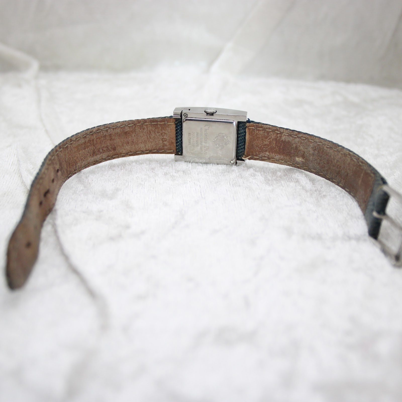 Back view of the Dior D78-109 watch showing the denim strap's leather lining and the case back engravings.