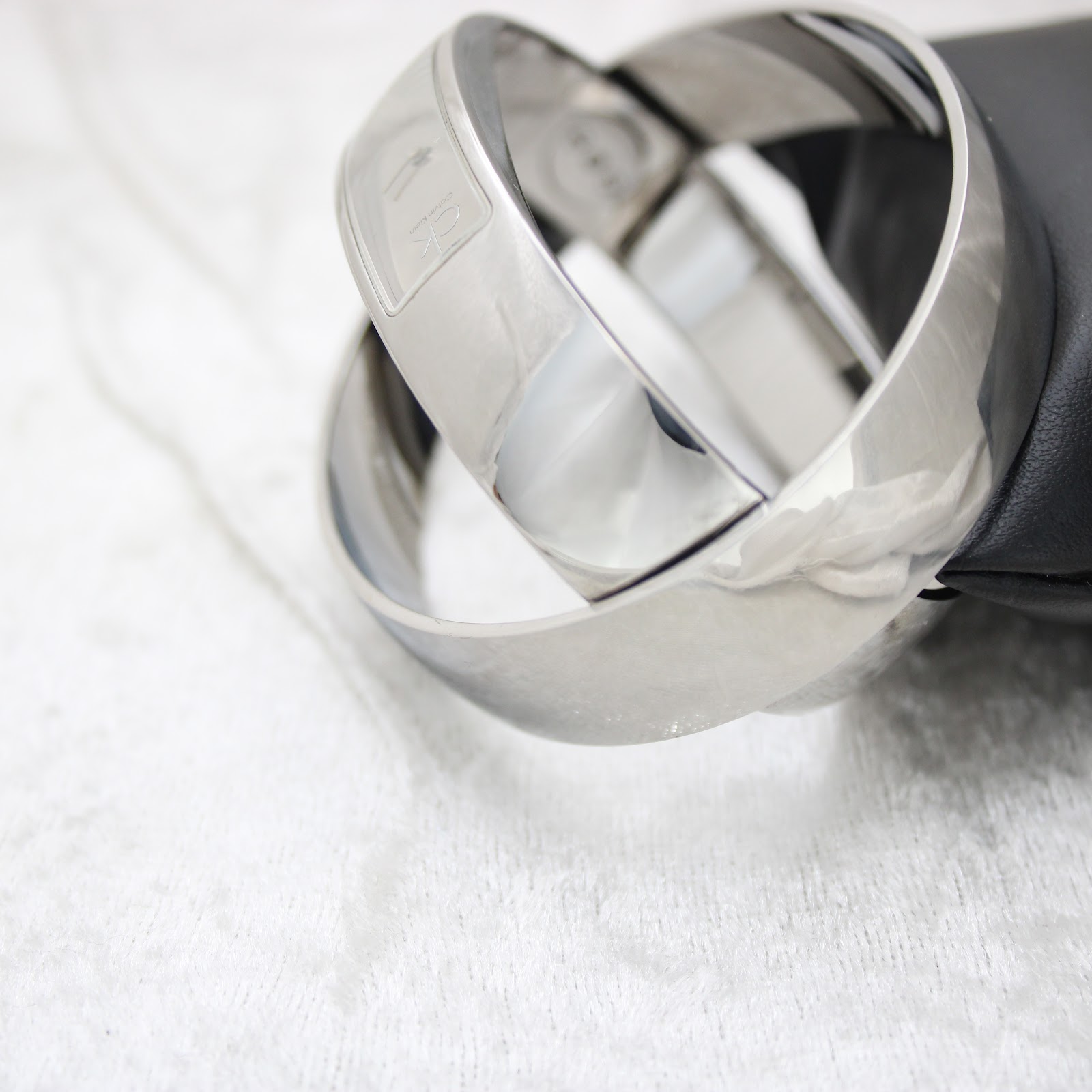 Angled view of the sleek, polished stainless steel Calvin Klein bangle watch resting on a black cushion.