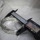 Digital caliper measuring the outer width of the integrated stainless steel bangle bracelet, showing 79.4 mm.