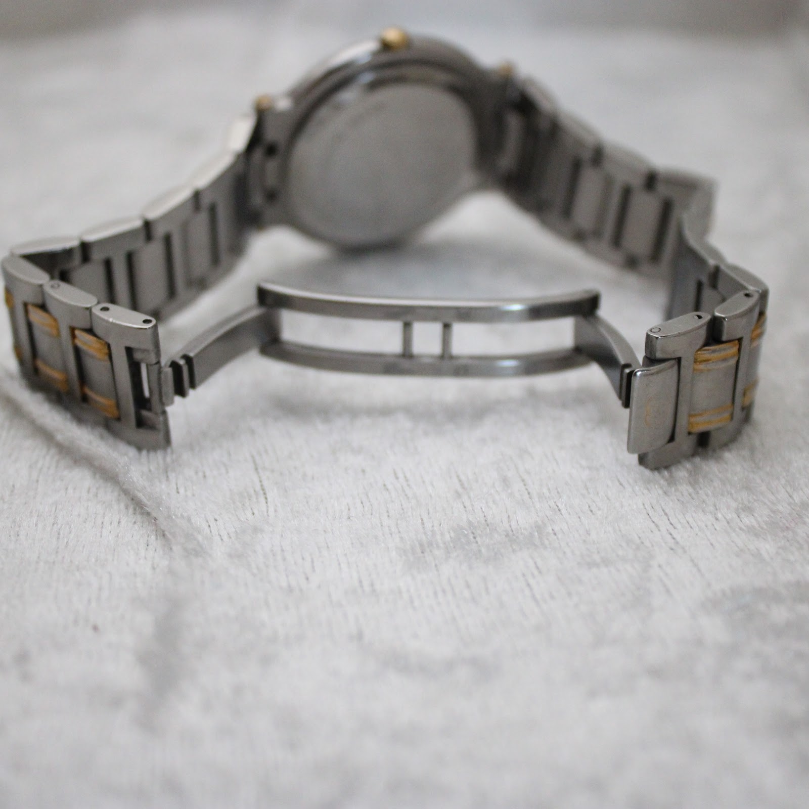 View of the open butterfly clasp on the two-tone bracelet of the Gucci 9000G, laid flat on a white surface.
