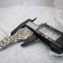 Digital caliper measuring the case diameter of the Gucci 9000G, showing a reading of '35.7 mm' on the display.