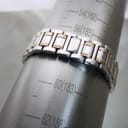 The two-tone bracelet of the Gucci 9000G on a wrist sizing gauge, indicating a wrist circumference of '183mm' (60).