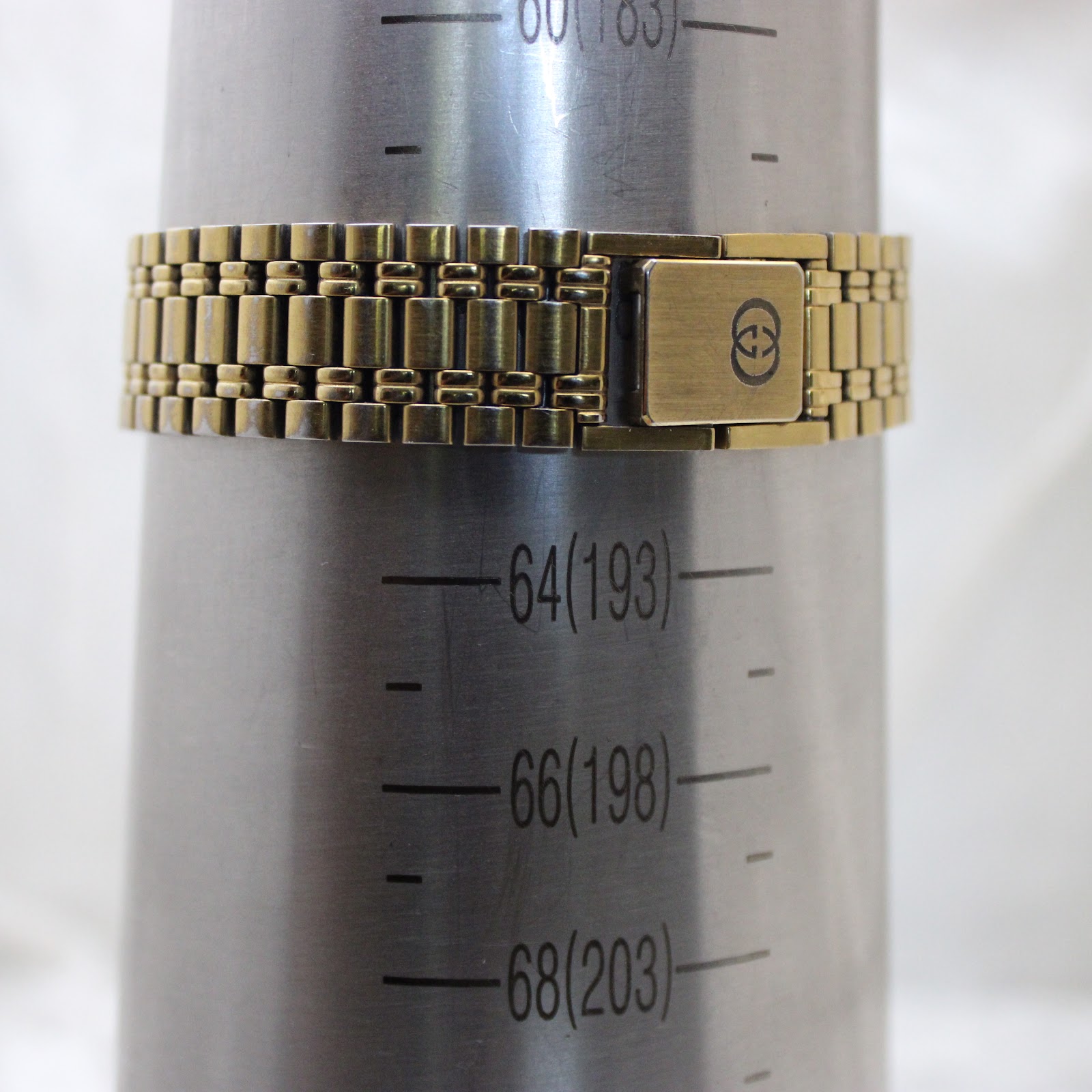 The gold-tone Gucci bracelet on a wrist sizing gauge, indicating a wrist circumference of approximately 190mm (19cm).