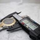 Close-up of a digital caliper measuring the watch case, displaying a precise diameter of 37.07mm.