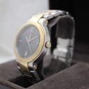 Angled side view of the Gucci 8900M watch, highlighting the gold-tone crown and two-tone bracelet, in its box.