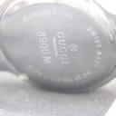 Extreme close-up of the stainless steel case back engraving, clearly showing 'GUCCI Timepieces', '8900 M', and 'SWISS MADE'.