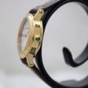 Side profile of the Gucci 7200L watch, highlighting the gold-tone case and green cabochon crown.