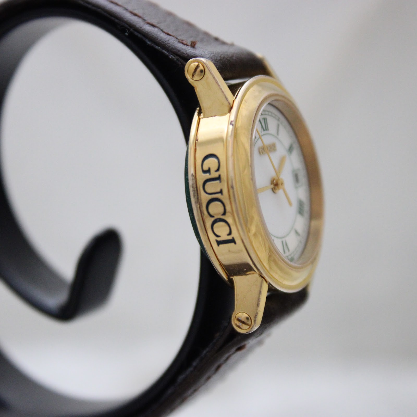 Angled side view of the Gucci 7200L watch, showing the 'GUCCI' engraving on the case side.