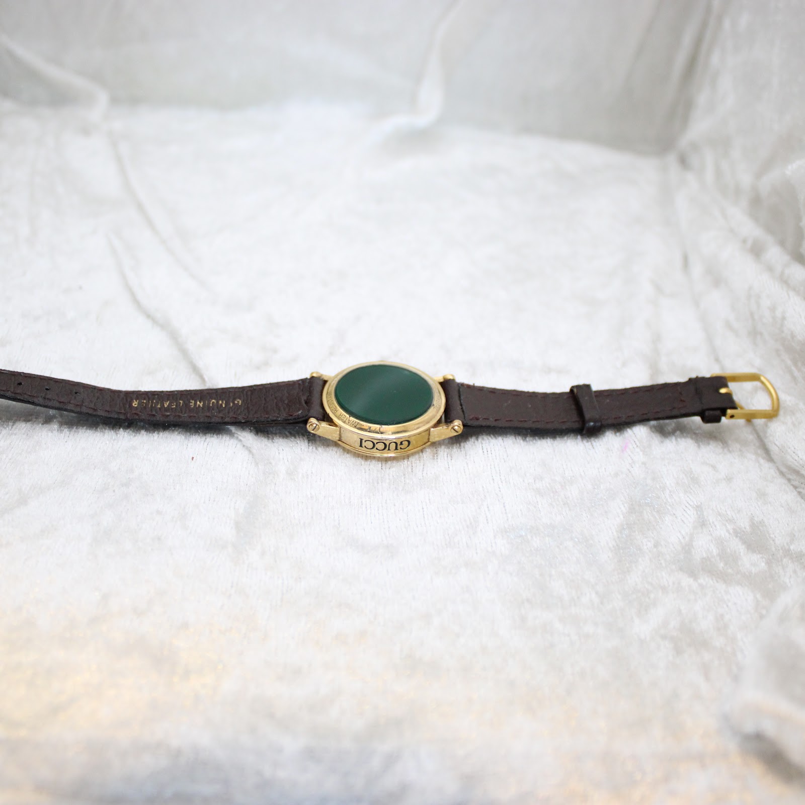 Full view of the Gucci 7200L watch and strap laid flat, showing 'GENUINE LEATHER' on the strap's underside.
