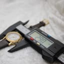 Digital caliper measuring the Gucci 7200L watch case, displaying a precise diameter of 29.0mm.