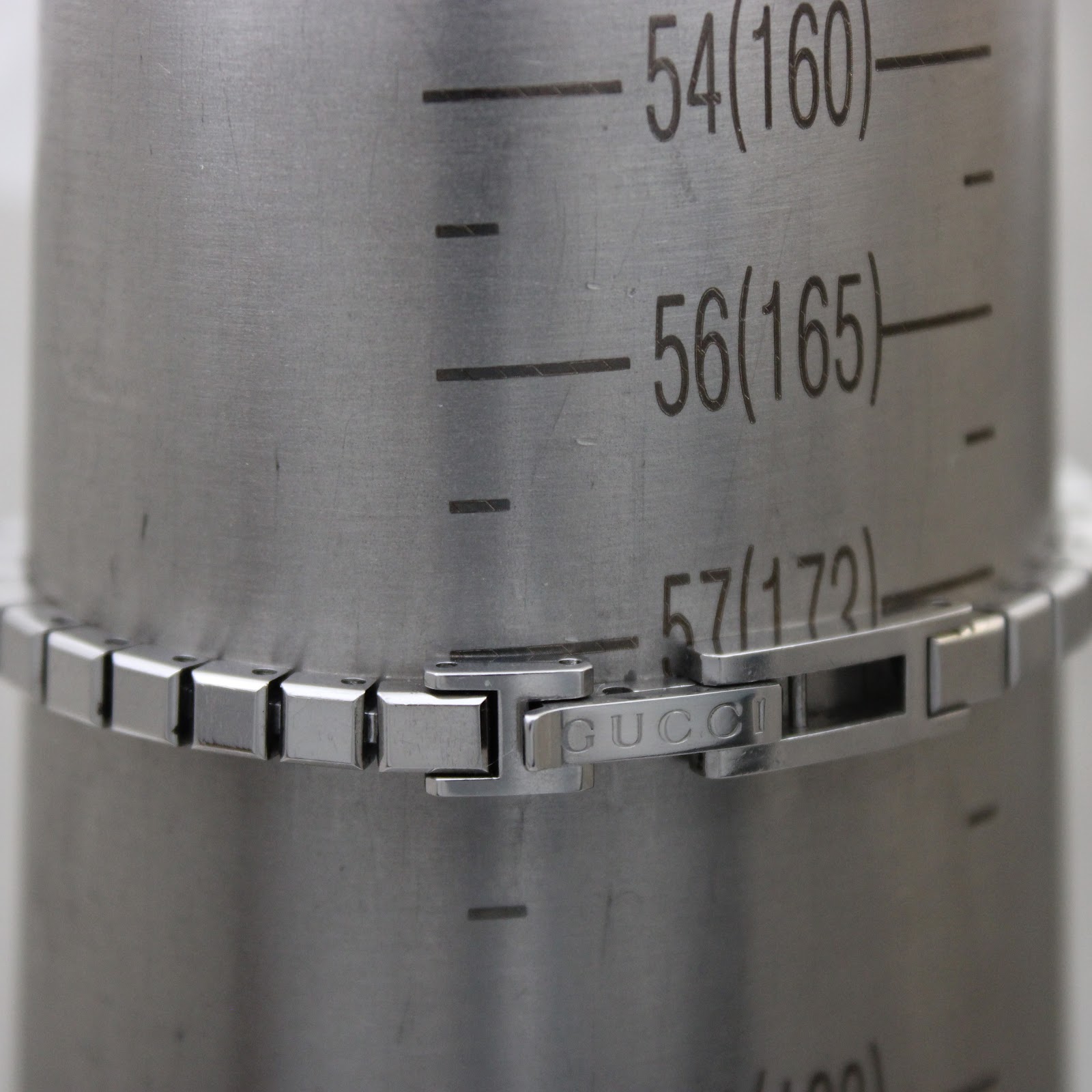 Close-up of the Gucci bracelet clasp on a wrist sizing gauge, showing 'Gucci' engraving and a wrist fit of 172mm (17.2cm).