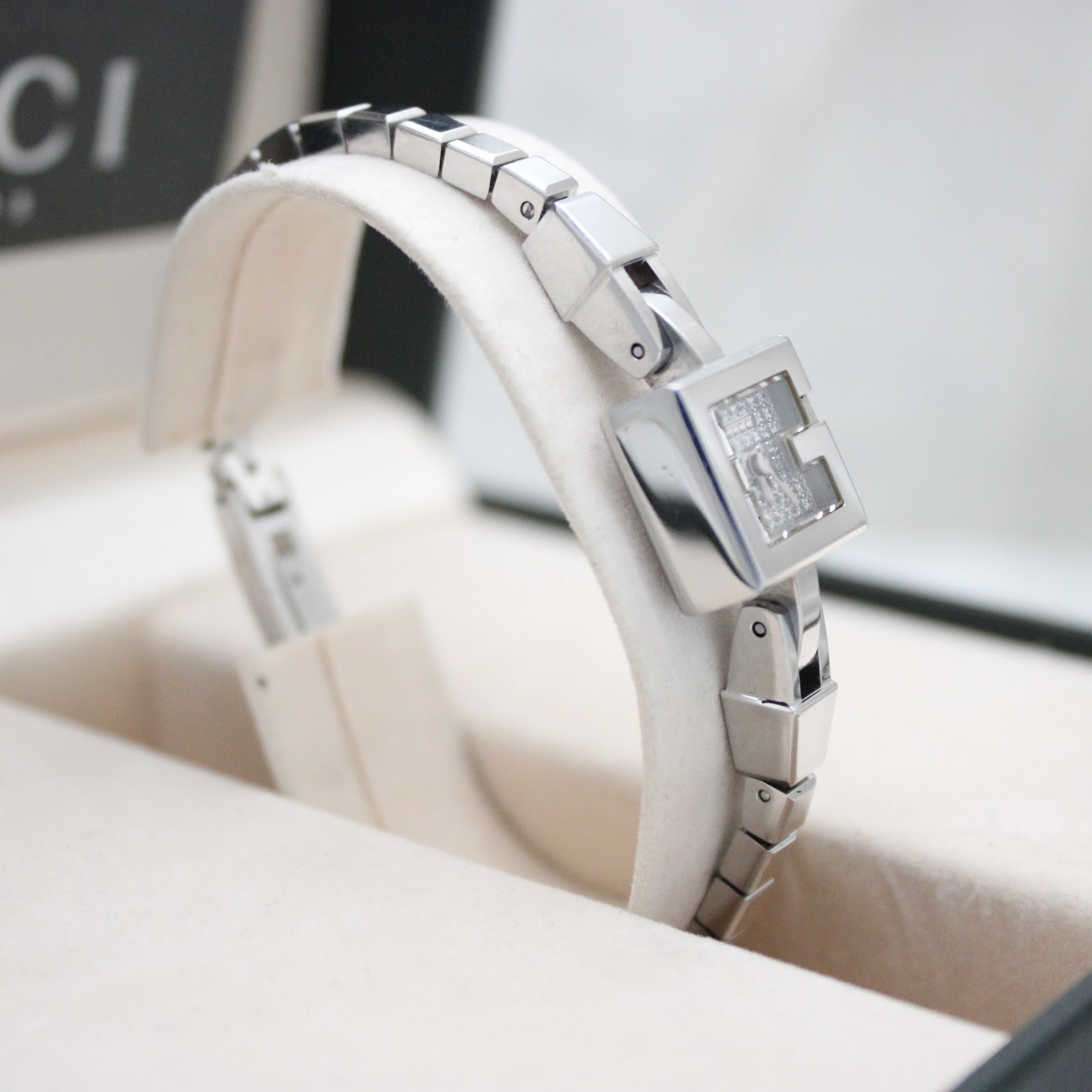 Angled view of the Gucci 102 G-frame watch on its display stand, within its original Gucci box.