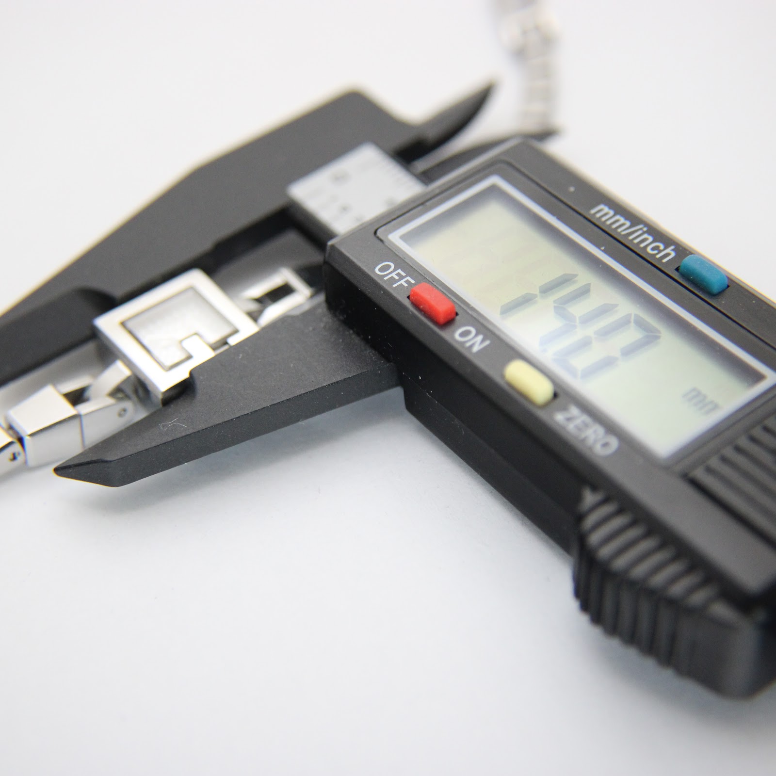 Digital caliper measuring the Gucci 102 G-frame watch case, showing a precise reading of 14.7mm.